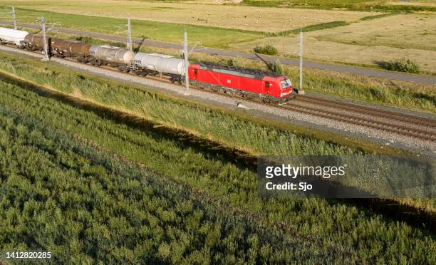 freight train pulling railroad cars on a railroad track in the countryside - rail freight stock pictures, royalty-free photos & images