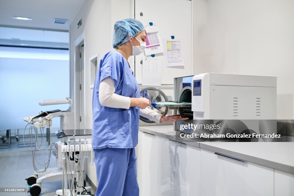 Female nurse doing sterilization of veterinarian medical instruments in autoclave