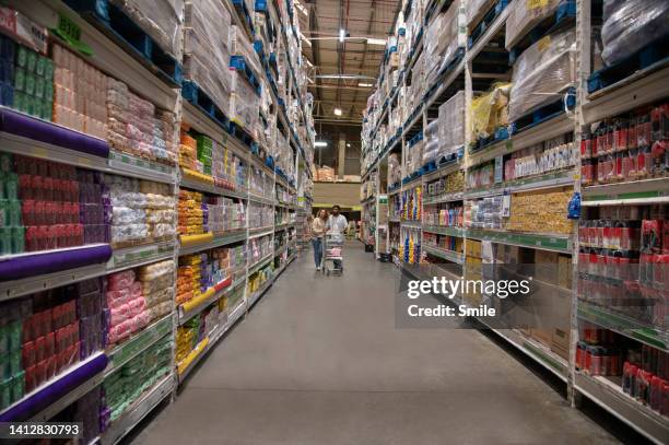 couple pushing a trolley down a supermarket aisle - shopping trolley photos et images de collection