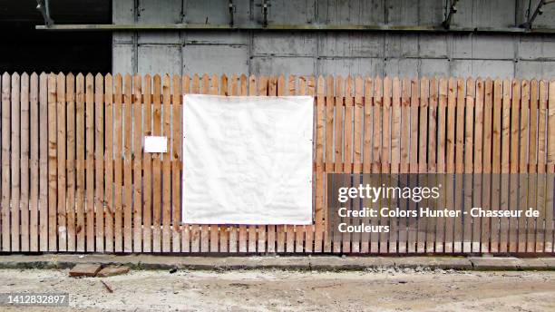 an empty white plastic tarpaulin on the palisade of a construction site and dirty street in brussels, belgium - poster wall stock-fotos und bilder