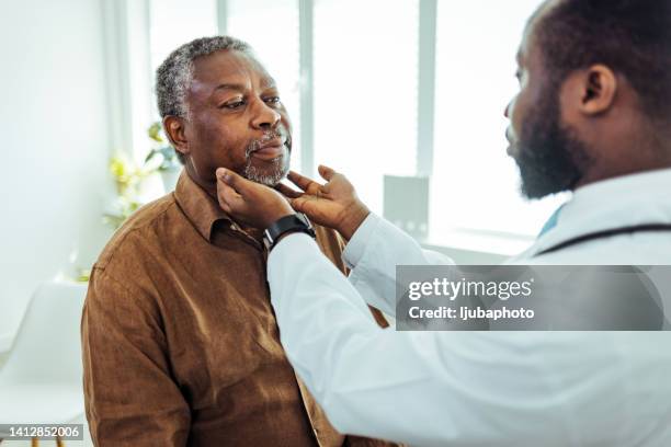 doctor doing throat examination on older man - screening of ill see you in my dreams arrivals stockfoto's en -beelden