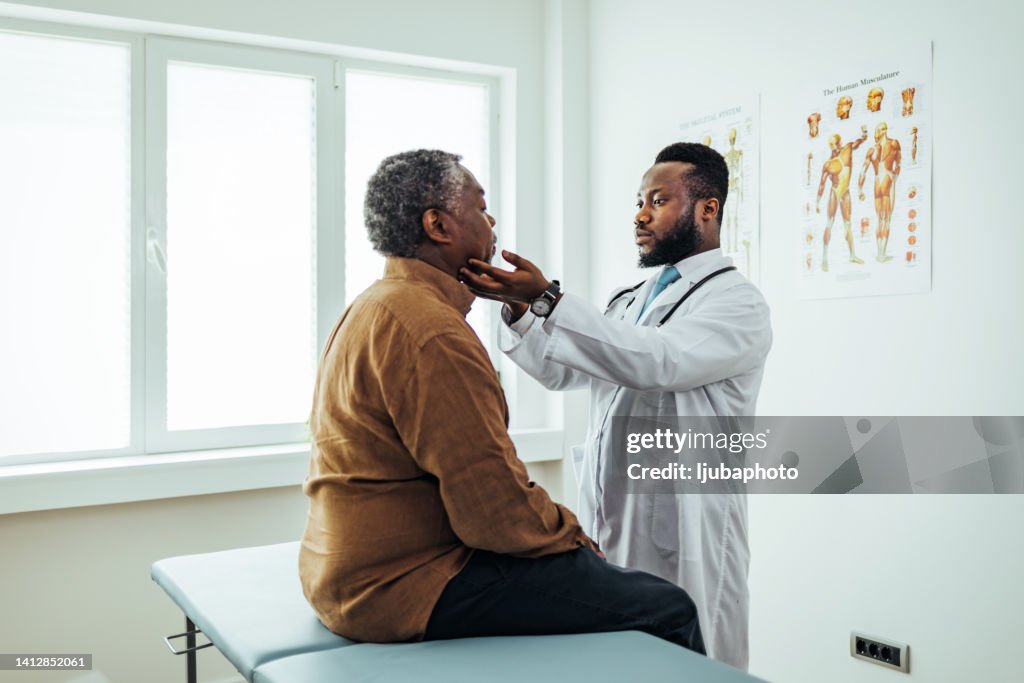 Médico do sexo masculino palpating pacientes linfonodos submandibulares