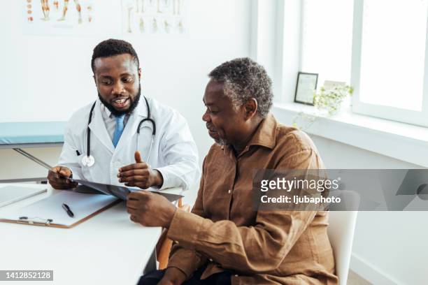 male doctor and senior patient discussing scan results at the office. - tentamenzaal stockfoto's en -beelden