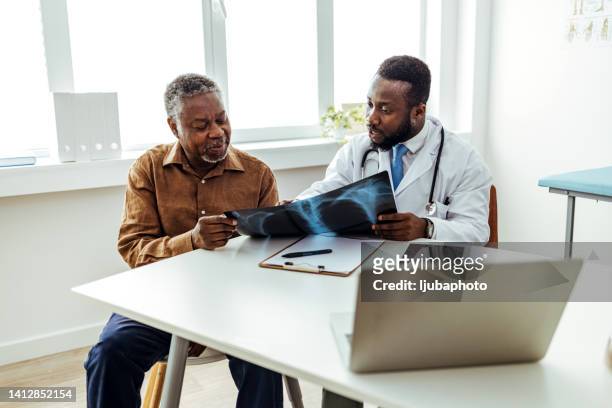 doctor smiling and giving good news to patient, showing him lung x-ray - human lung stock pictures, royalty-free photos & images