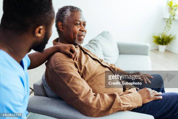 trabajador social está visitando a un hombre de la tercera edad - african american man helping elderly fotografías e imágenes de stock