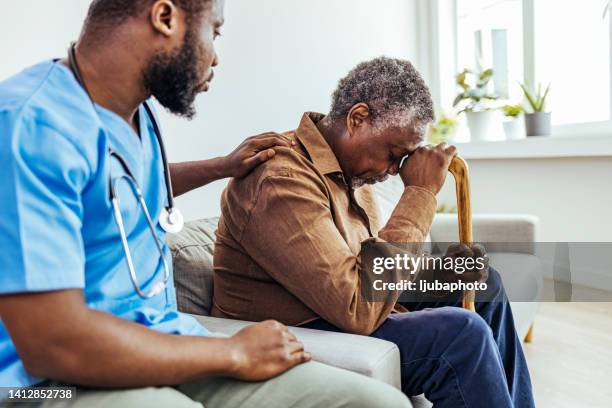 male professional doctor touching shoulder, comforting upset senior patient. - stress test stockfoto's en -beelden