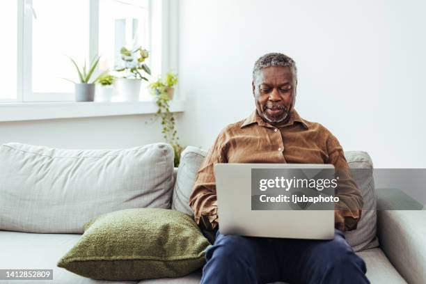 senior man working at laptop at home - senior men computer stock pictures, royalty-free photos & images