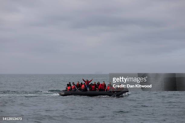 An inflatable craft carrying migrants crosses the shipping lane in the English Channel on August 4, 2022 off the coast of Dover, England. Around 700...