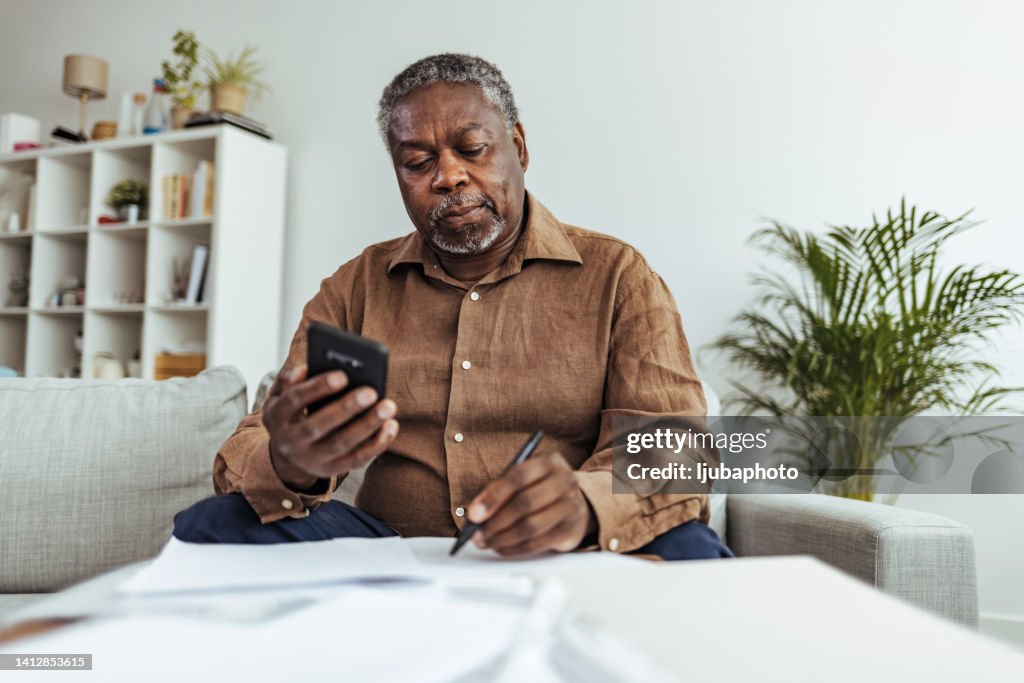 Mature businessman working at home using smart phone