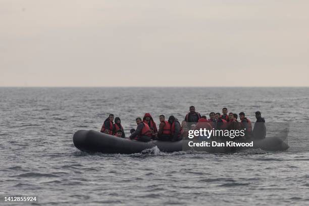 An inflatable craft carrying migrants crosses the shipping lane in the English Channel on August 4, 2022 off the coast of Dover, England. Around 700...