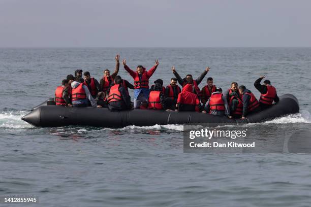 An inflatable craft carrying migrants crosses the shipping lane in the English Channel on August 4, 2022 off the coast of Dover, England. Around 700...