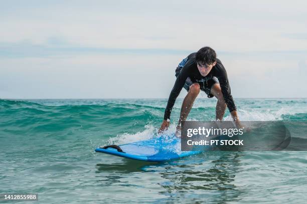 a man in a bathing suit is surfing in the sea - indonesia surfing imagens e fotografias de stock