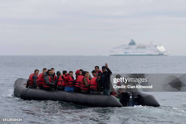 An inflatable craft carrying migrants crosses the shipping lane in the English Channel on August 4, 2022 off the coast of Dover, England. Around 700...