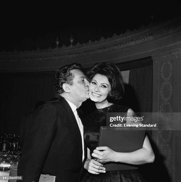 British-born Australian actor Peter Finch kissing the cheek of Italian actress Sophia Loren at the 15th British Academy Film Awards, London, England,...