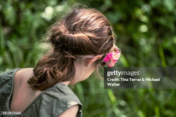 young girl playing in the garden. view from behind. - adorno floral fotografías e imágenes de stock