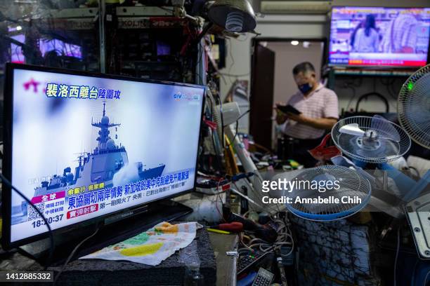 Television shows a news broadcast about China conducting a live fire drill around Taiwan at a local electrical repair store after Speaker of the...