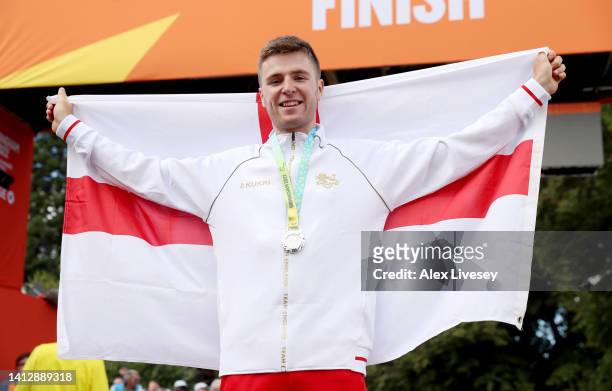 Silver Medalist, Fred Wright of Team England celebrates with their flag during the Men's Individual Time Trial medal ceremony on day seven of the...