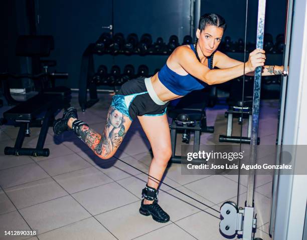 attractive athletic woman doing leg curl with elastic rope in the gym. young woman doing calf curls with elastic rope in the gym, concept of sporty woman in a gym doing leg curls - female muscular calves fotografías e imágenes de stock