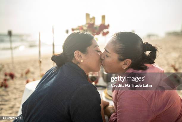 lesbian couple kissing in the dinner on the beach - lesbian couple stock pictures, royalty-free photos & images