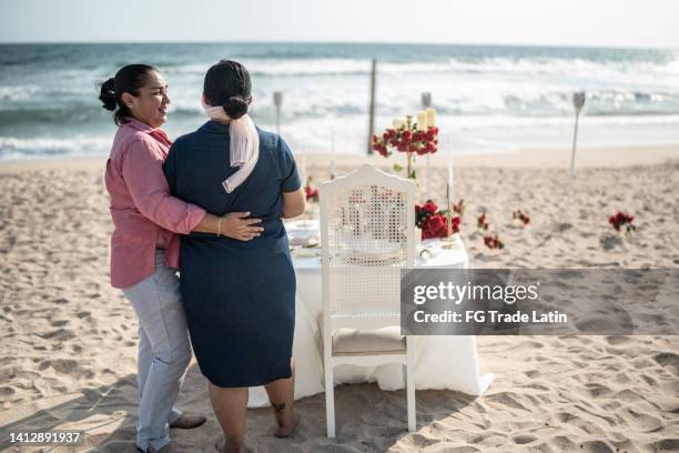 lesbian woman making a surprise to her wife with eyes with a blindfold on the beach - restraining device stock pictures, royalty-free photos & images