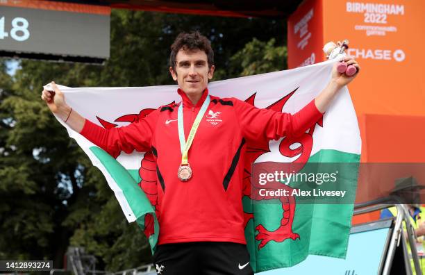 Bronze Medalist, Geraint Thomas of Team Wales celebrates with their flag during the Men's Individual Time Trial medal ceremony on day seven of the...