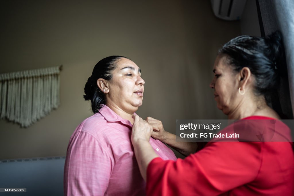 Mother helping daughter getting dressed at home