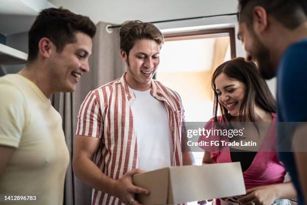 young man receiving gift from friends at home - house warming stock pictures, royalty-free photos & images