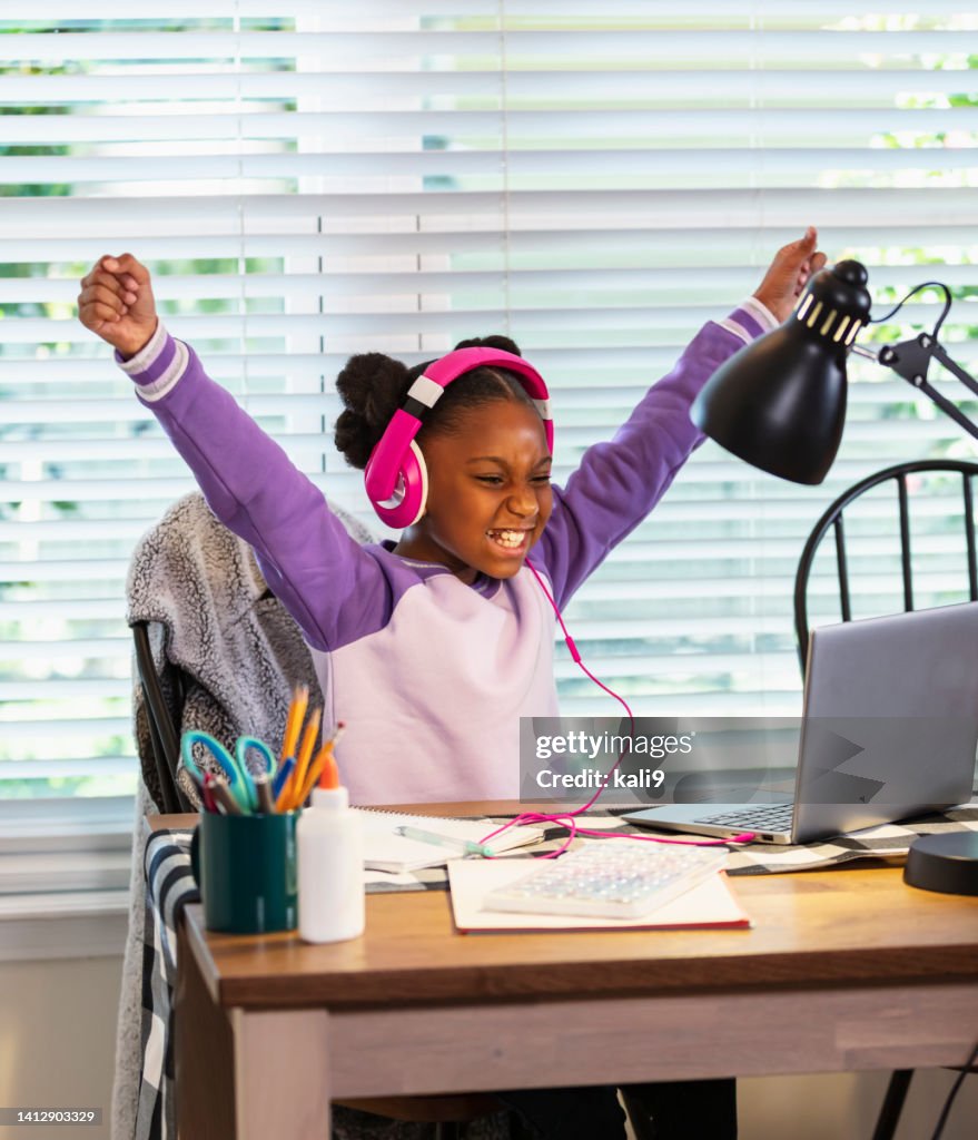 Elementary school girl e-learning from home, excited