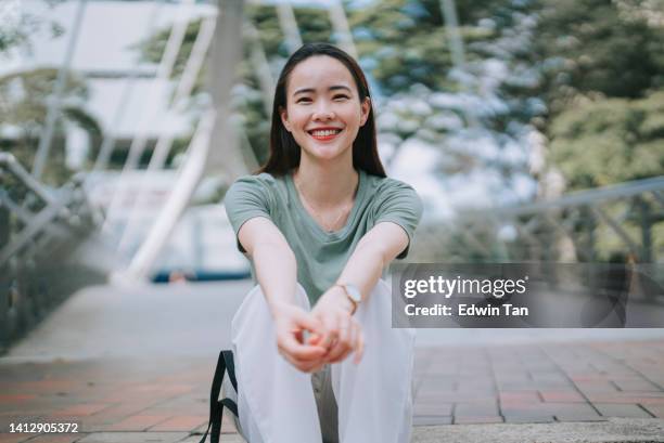 asian chinese beautiful woman looking at camera sitting on ground smiling - chinese people posing for camera stockfoto's en -beelden