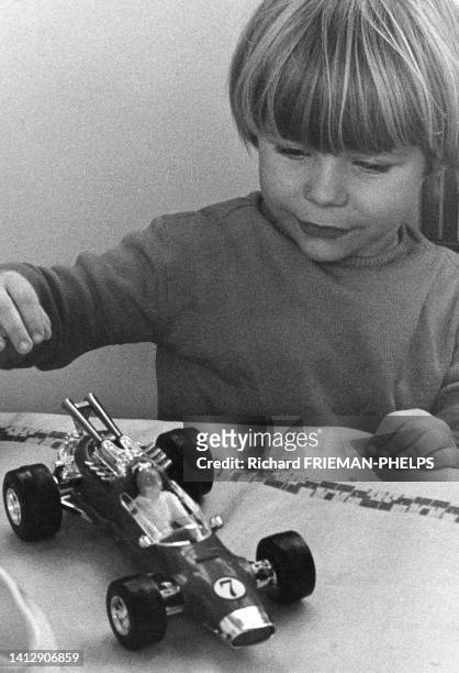 Enfant jouant avec une voiture de course, dans les années 1970.