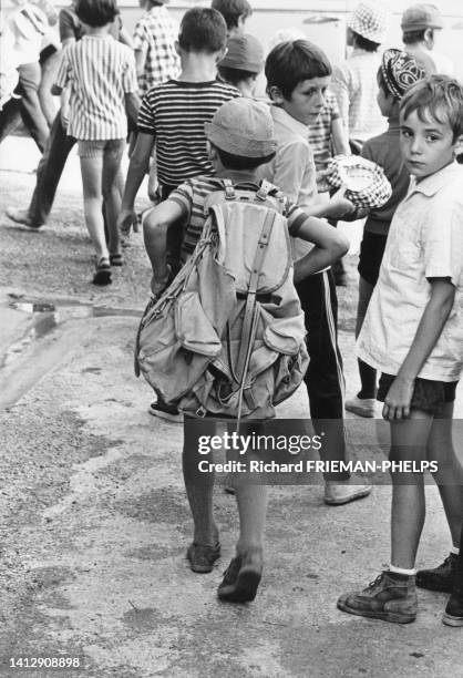 Enfant portant un grand sac à dos en colonie de vacances, dans les années 1970.