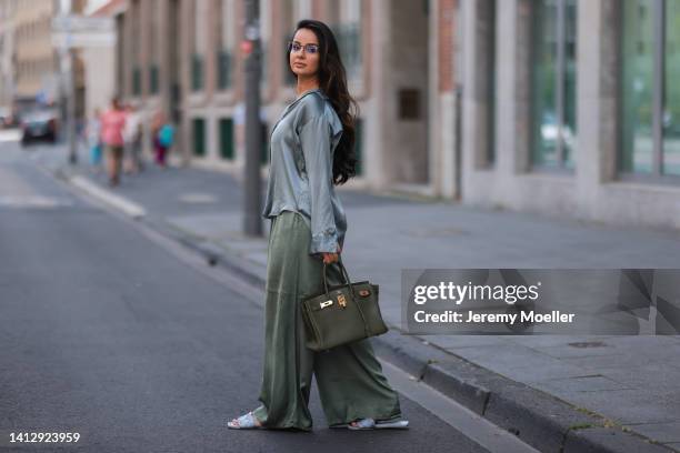 Tara Tut, aka tamtambeauty, wearing a Hermes olive Birkin Bag, a blue silk shirt, olive Sassyclassy pants, blue H&M sandals and Prada glasses on...