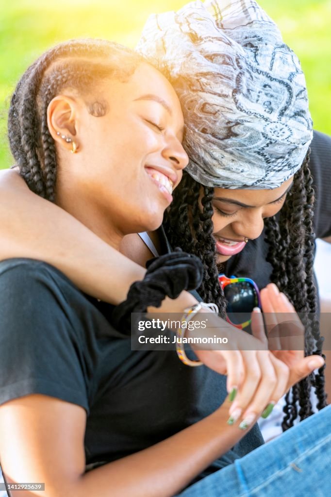 Afro-Latinx verspielte junge Lesben, die in einem Park reden und lachen