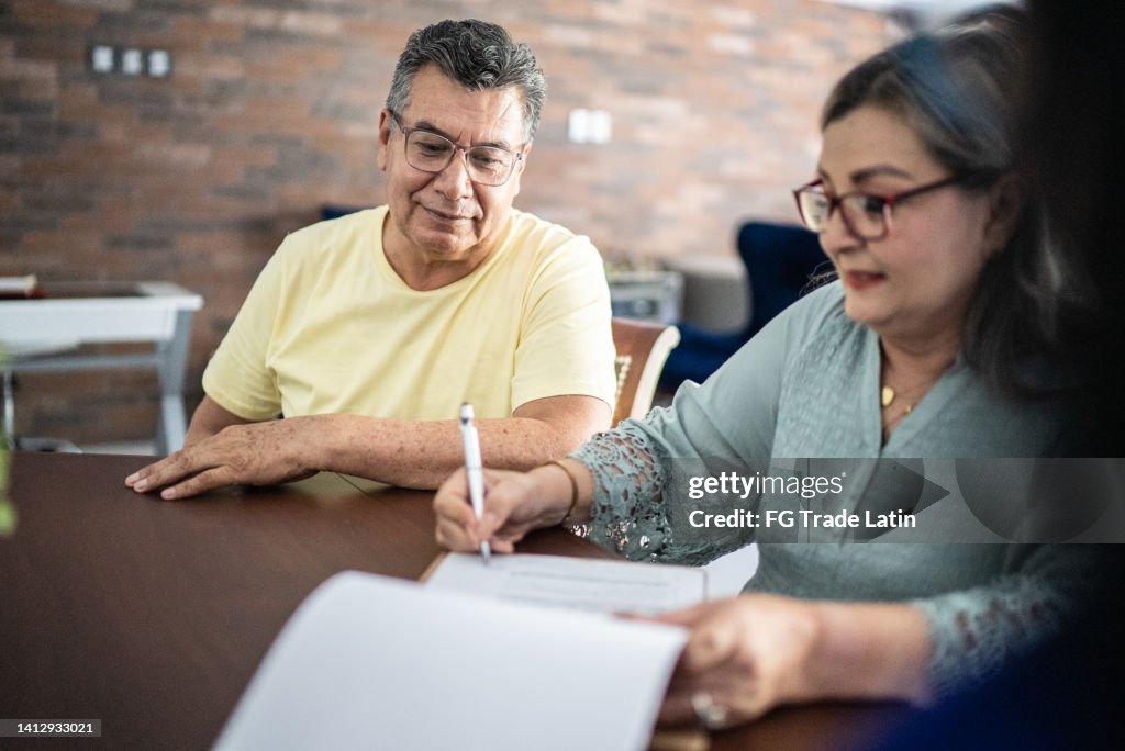 Senior couple signing contract to buy a house