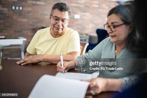 senior couple signing contract to buy a house - preencher um formulário imagens e fotografias de stock