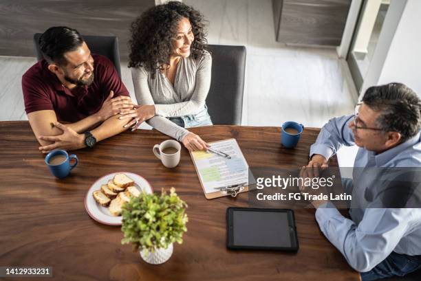 mid adult couple having a meeting with real estate agent (or financial advisor) at house - spanish royals host a lunch for president of mexico and his wife stockfoto's en -beelden