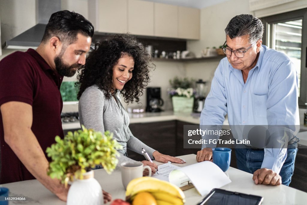 Mid adult couple filling document in the kitchen at home
