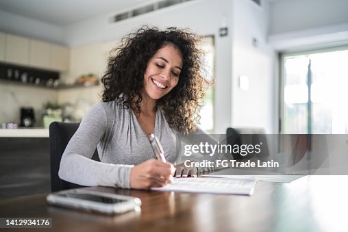 Mid adult woman filling document at home Mid adult woman filling document at home