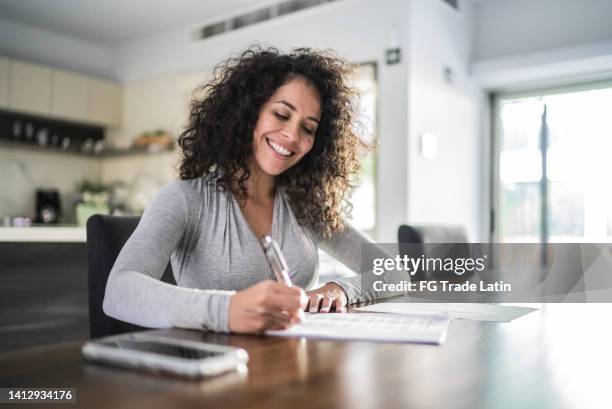 mid adult woman filling document at home - form filling stock pictures, royalty-free photos & images