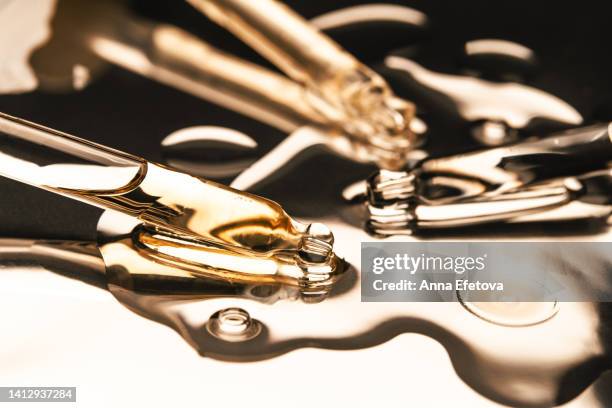 three glass pipettes with liquid with baubles. care cosmetics with peptides, ceramides, retinol molecules concept. oil or hyaluronic or polyglutamic acid - jojoba oil stock pictures, royalty-free photos & images