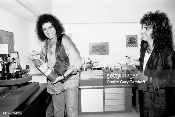 View of American Rock musicians Gene Simmons , a fire extinguisher in his hands, and Paul Stanley , both of the group Kiss, clown around at Sterling...