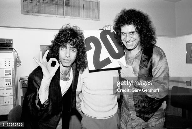 Portrait of American Rock musicians Paul Stanley and Gene Simmons , both of the group Kiss, on either side of mastering engineer George Marino , the...