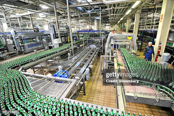 An employee watches as bottles of lager move along a conveyor belt at the Carlsberg A/S production plant in Kiev, Ukraine, on Wednesday, March 14,...