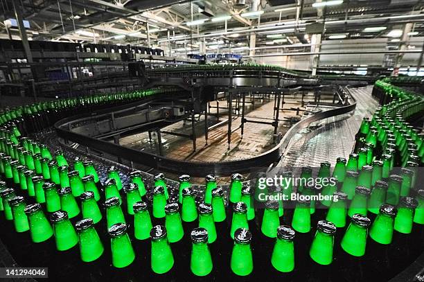 Bottles of lager move along a conveyor belt before labelling at the Carlsberg A/S production plant in Kiev, Ukraine, on Wednesday, March 14, 2012....