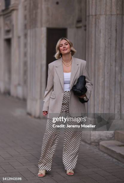 Franzi Koenig wearing striped H&M pants, a beige oversize blazer, a white samsoe samsoe top, Fafe Collection jewelry, a black leather bag and beige...