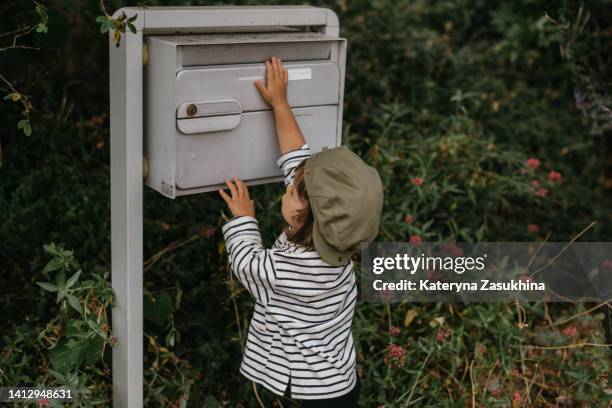 a little girl in a stylish outfit checking the mail box - briefkasten stock-fotos und bilder