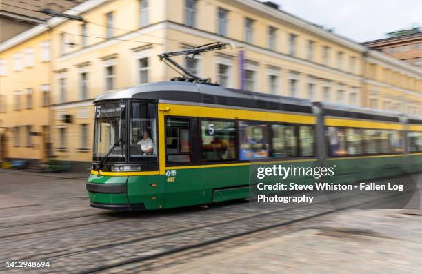 green and yellow electric tram cars passing by in downtown helsinki by senate square with background of pale yellow buildings - helsinki urban stock-fotos und bilder