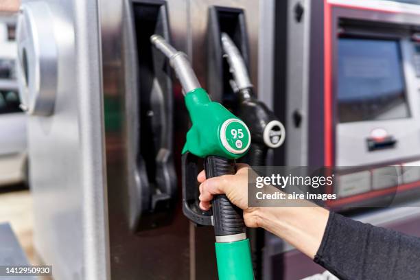placing the refueling hose on the pump after putting gas in your car to be able to continue on your way. - benzintank stock-fotos und bilder