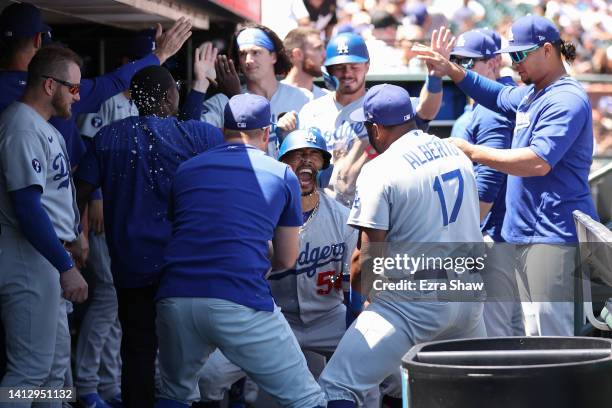 Mookie Betts of the Los Angeles Dodgers is congratulated by teammates in the dugout after he hit a home run in the fourth inning against the San...