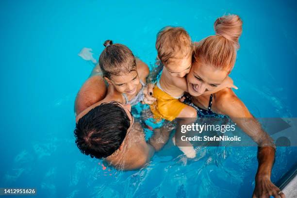 glückliche familie im pool - baby swimmer stock-fotos und bilder
